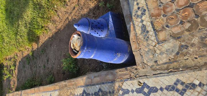 Blue ceramic garden container used as a trash bin beside patterned walkway.