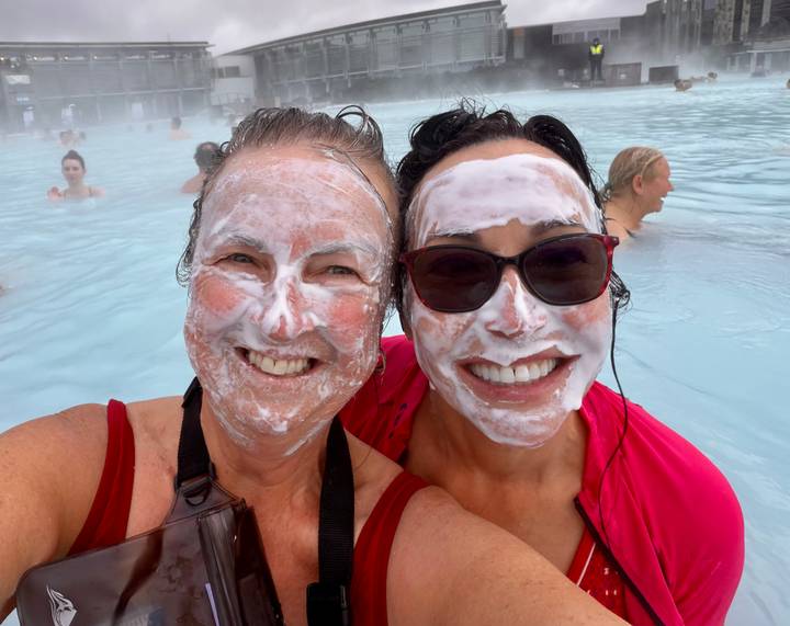 Bathers with white silica masks grin in the milky blue waters of the Blue Lagoon spa.