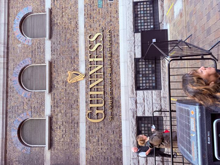Exterior wall of the Guinness Storehouse with its iconic gold harp logo and visitors milling about.