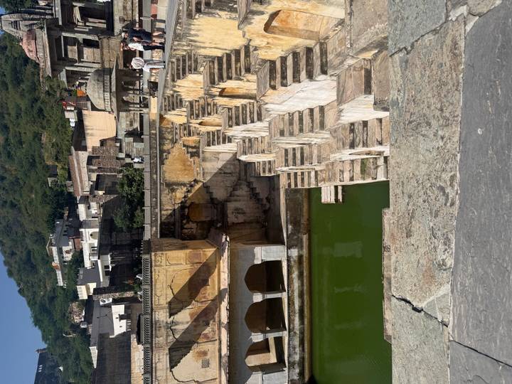 Stone staircases cascade into a green water tank at the historic Panna Meena ka Kund stepwell.