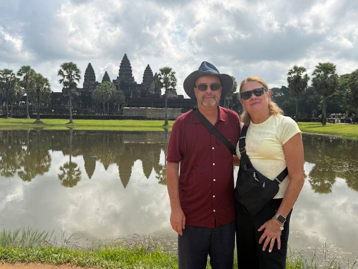 Couple posing by the reflecting pond with the towers of Angkor Wat rising behind them.