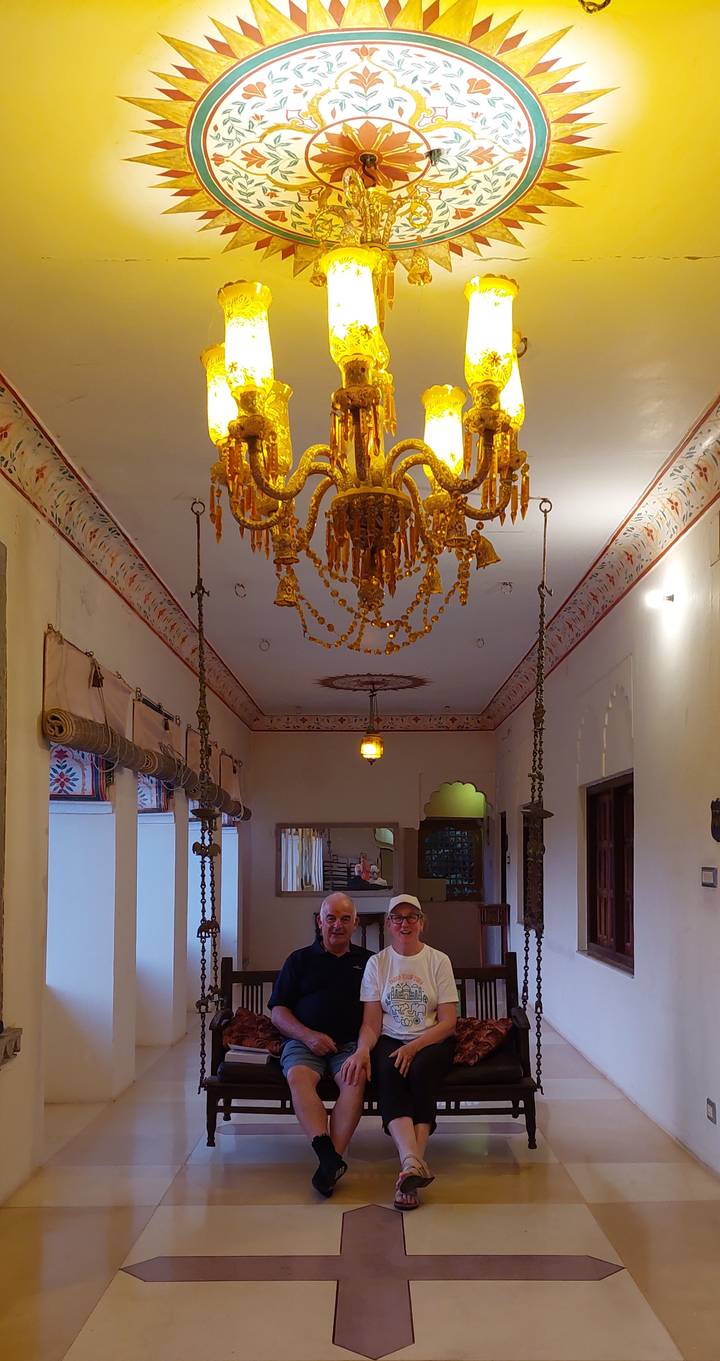 Ornate chandelier and painted ceiling details inside a heritage Indian corridor.