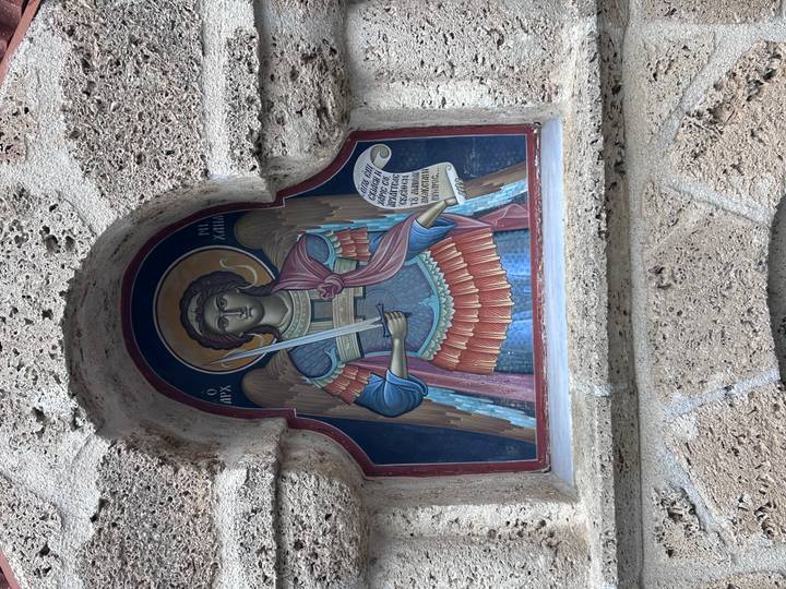 Colorful religious fresco of Archangel Michael framed in a stone niche.