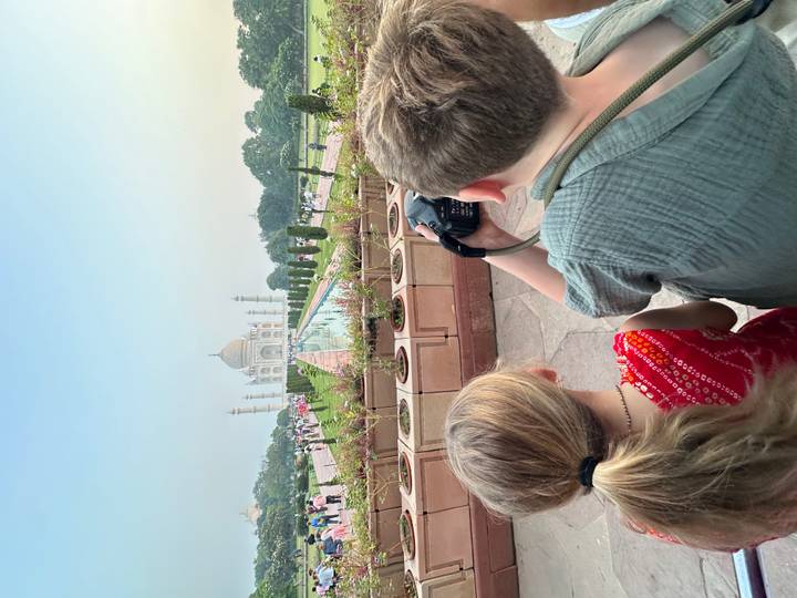 Two children view and photograph the Taj Mahal from the reflecting pool walkway.