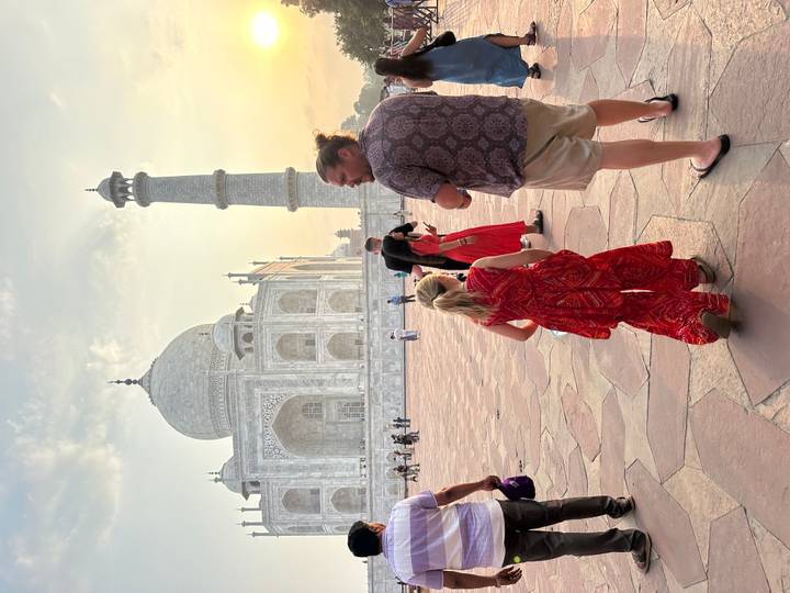 Visitors walk across the marble courtyard beside the Taj Mahal in warm afternoon light.