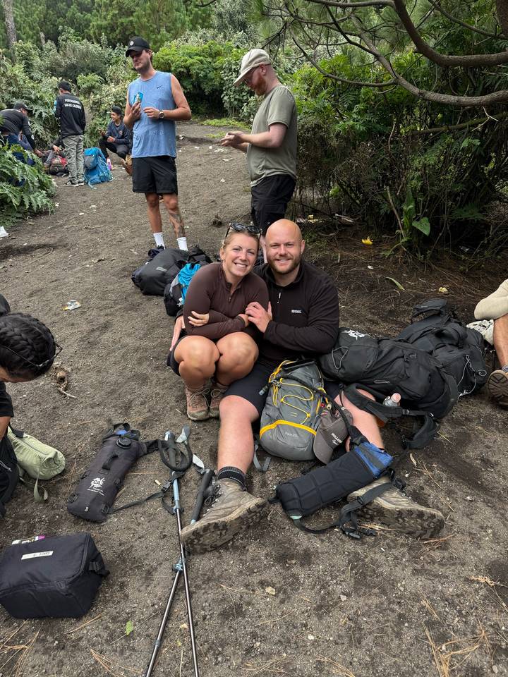 Hikers rest on the forest floor surrounded by backpacks after a mountain trek.
