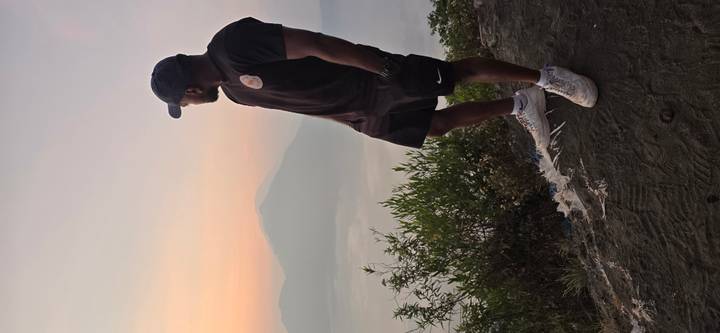 A traveler gazes at a misty volcanic lake and peak during sunrise.