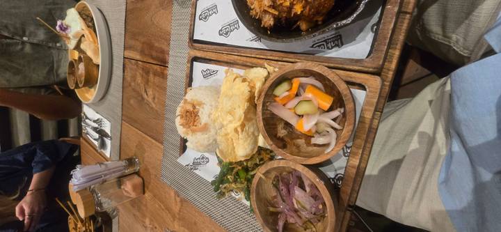 Traditional Indonesian meal served on wooden trays with assorted side dishes.