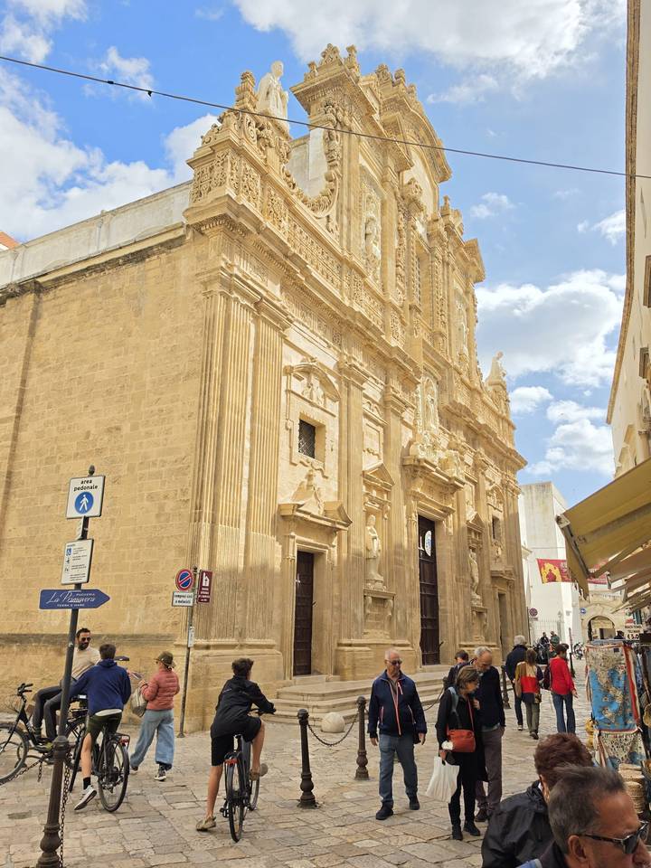 Baroque sandstone church façade glowing under a blue-sky afternoon.