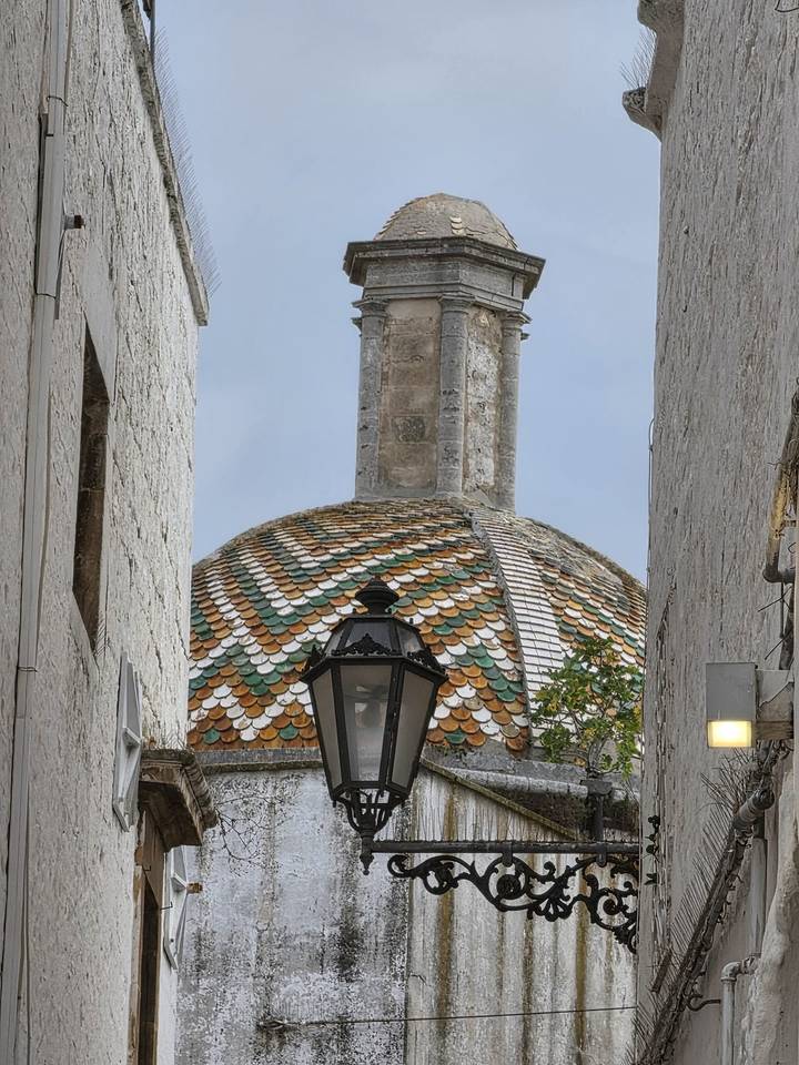 Colourful tiled dome and lantern framed tightly between white stone walls.