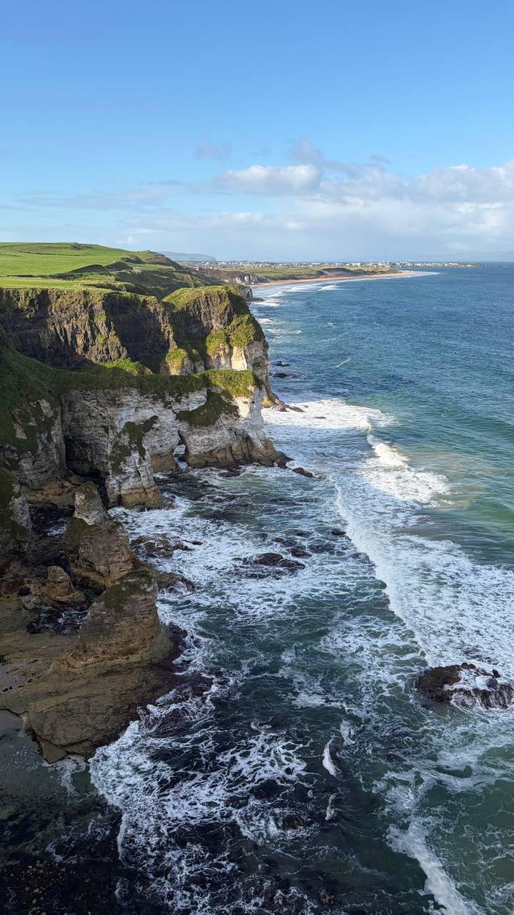 Dramatic seaside cliffs and sea stacks battered by waves along Northern Ireland’s rugged coast.