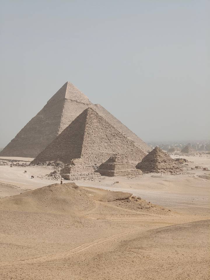 Iconic pyramids of Giza rise from the desert sands with smaller satellite pyramids nearby.