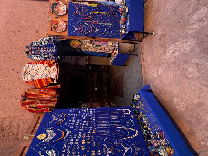 Colorful Berber jackets, jewelry and handicrafts displayed at a small market stall.