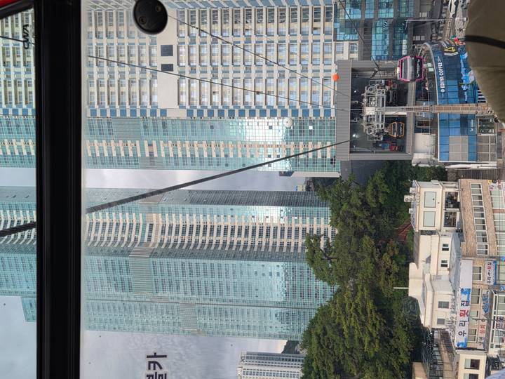 Tall glass skyscrapers seen through the window of a cable car ascending the urban hillside.