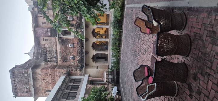 Courtyard of an old stone palace with circle of wicker chairs on a brick patio at dusk.