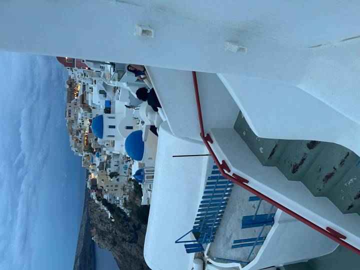 Blue-domed churches and whitewashed houses of Oia terraces glow in the evening light.