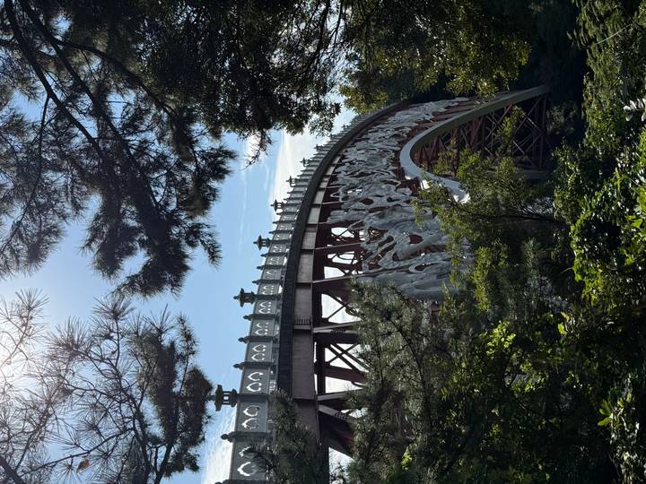 Decorative arched pedestrian bridge with carved figures seen through forest trees