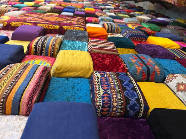 Close-up of stacked colourful Central Asian textile cushions in a market stall.