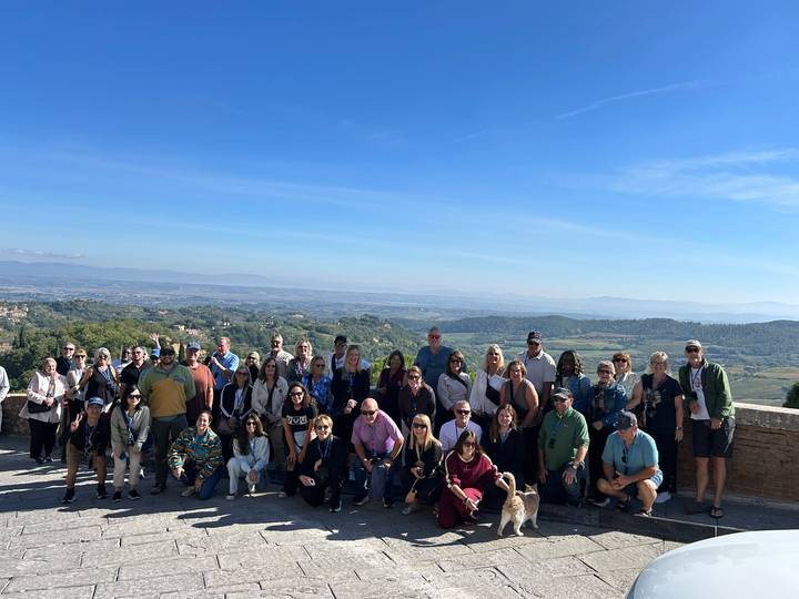 Large tour group gathers on a hilltop terrace overlooking rolling Umbrian countryside.