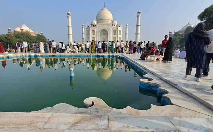 Large crowd lining the reflecting pool in front of the iconic Taj Mahal
