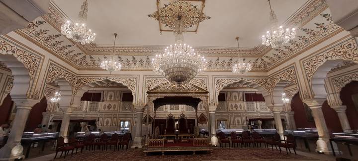 Opulent palace hall with chandeliers, ornate arches and a royal throne display