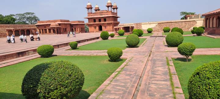 Symmetrical Mughal courtyard with manicured hedges and red sandstone buildings at Fatehpur Sikri