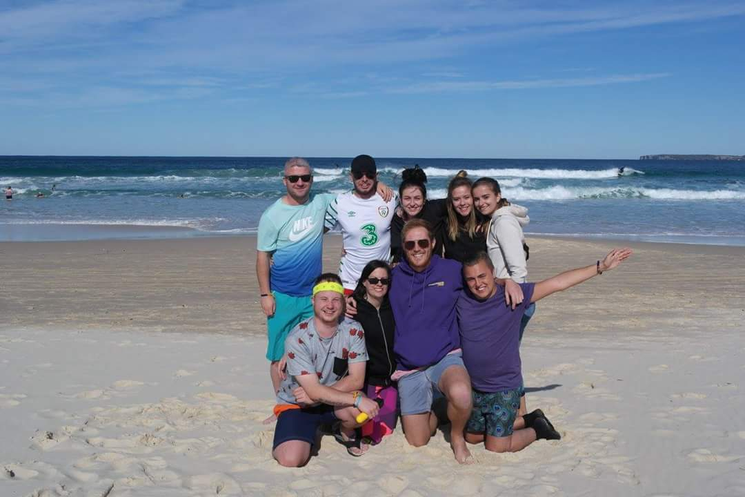 A group of people posing on a sandy beach.