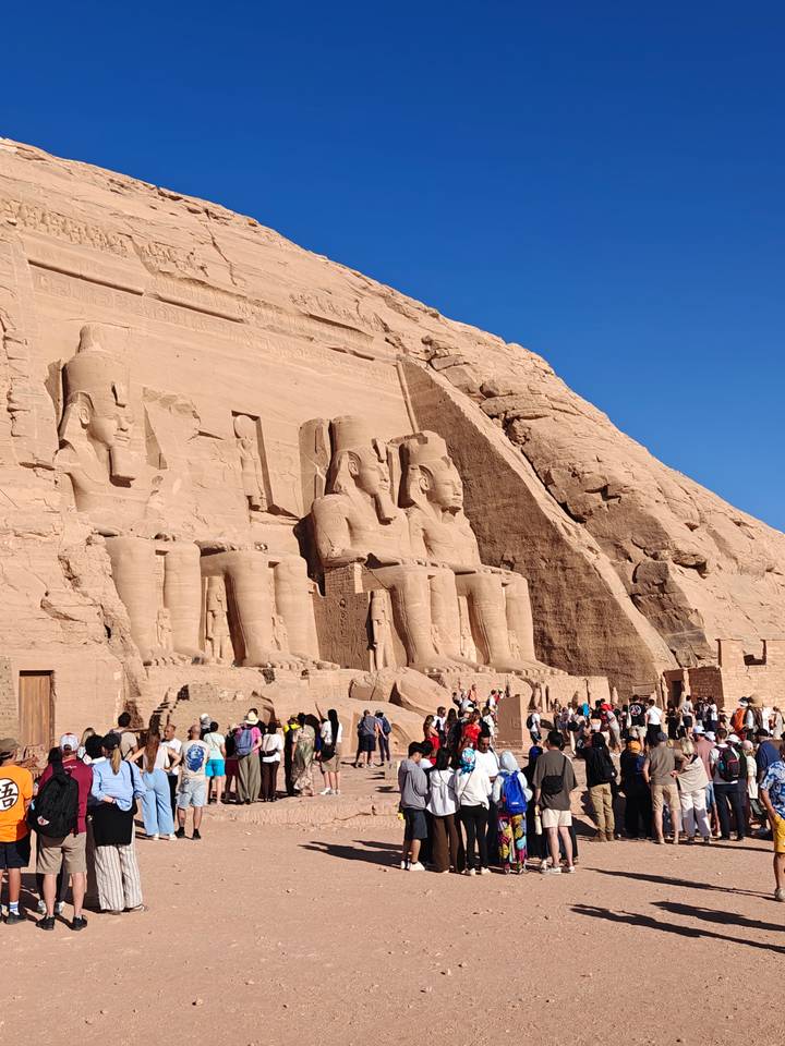 Crowds gather in front of the colossal seated statues carved into the cliff at Abu Simbel temple.