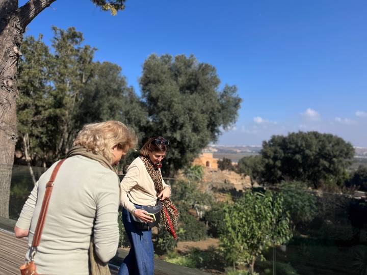 Travellers pause beside lush garden terraces overlooking a distant cityscape