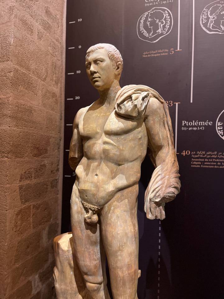 Classical marble statue displayed under focused lighting inside a museum gallery