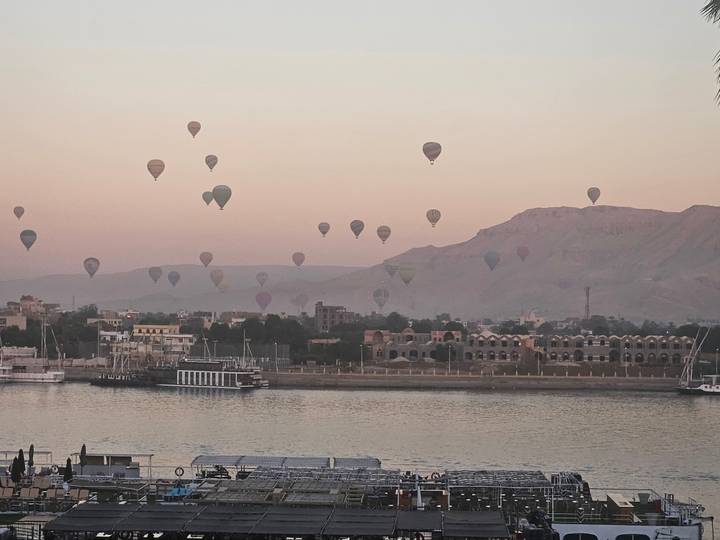 Dozens of hot-air balloons rising at dawn over the Nile River and Luxor’s west bank hills.