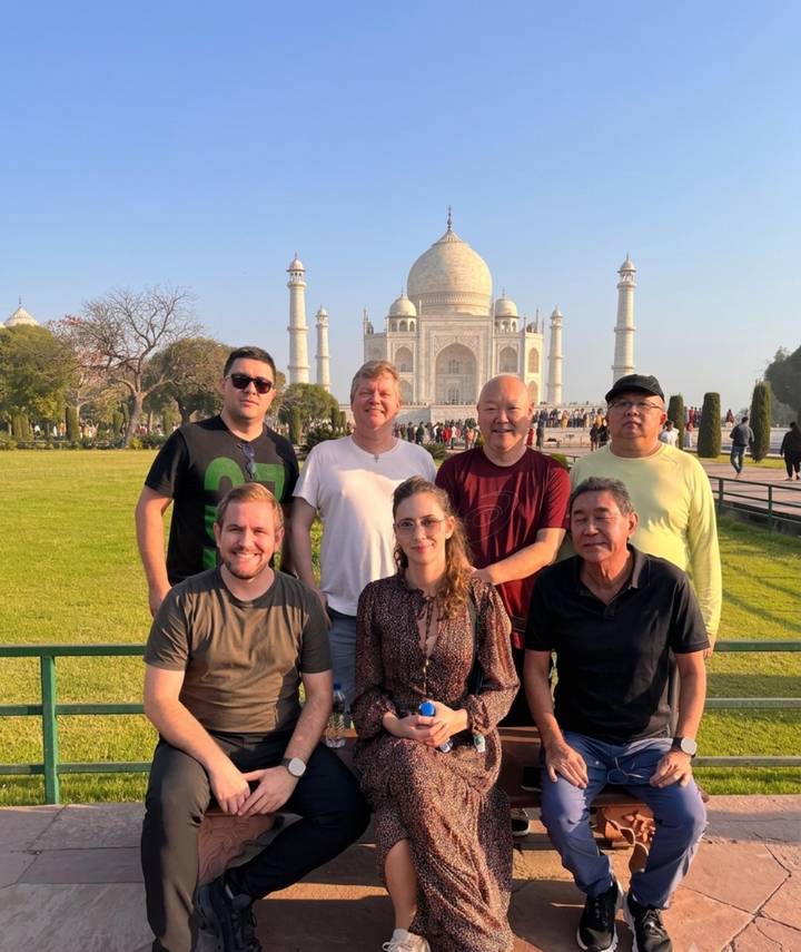 Group of travellers smiling with the Taj Mahal in the distant background