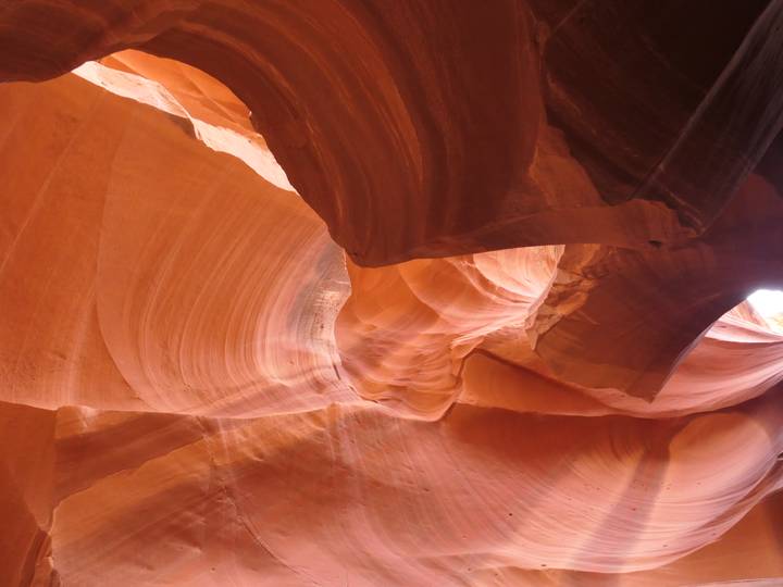 Soft light reveals the swirling red sandstone curves inside Antelope Canyon.
