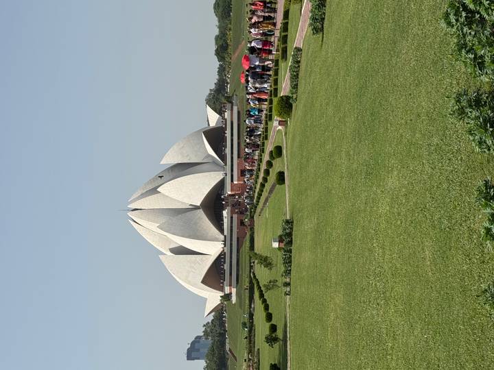 Lotus Temple's white petal-shaped structure rising above manicured lawns with a long queue of visitors.