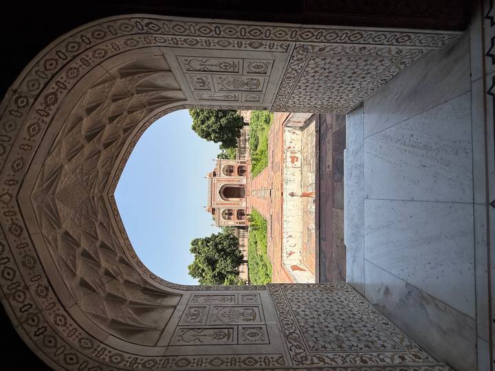 View through a marble archway toward the ornate gateway of Humayun's Tomb, India.