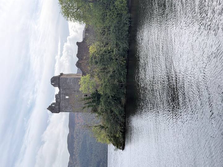 Ruins of Urquhart Castle situated on a promontory jutting into the dark waters of Loch Ness.