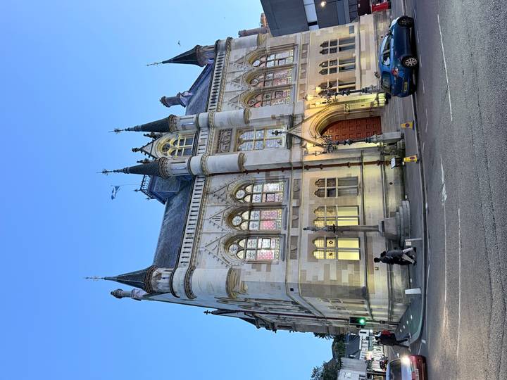 Elegant Victorian building with stained glass windows and spires illuminated at dusk on a city street.