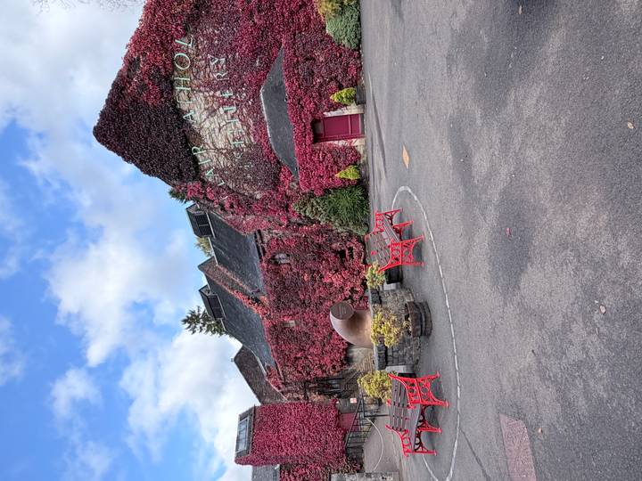 Distillery buildings covered in deep red ivy with red benches and a copper still sculpture in the courtyard.