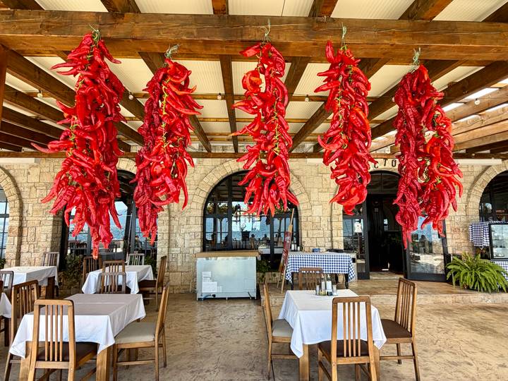 Restaurant interior decorated with rows of bright red dried peppers hanging from the ceiling.