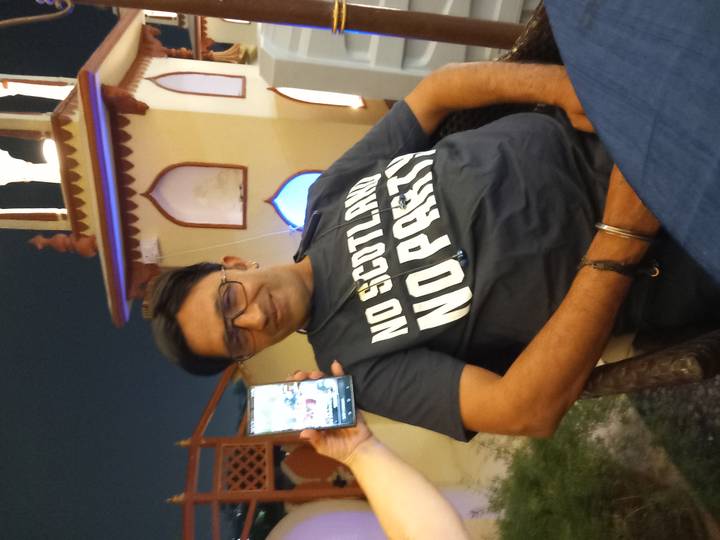 Night-time portrait of a man wearing a slogan T-shirt at an outdoor cafe.