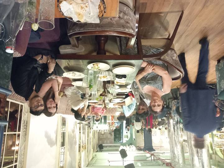Family and friends sitting around a dinner table in a busy restaurant.