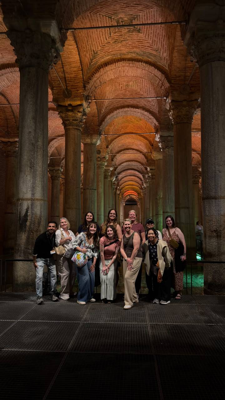 Group photo inside the dramatic arched columns of Istanbul's Basilica Cistern lit with warm tones.