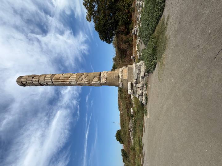 Tall solitary stone column from the Temple of Artemis stands against a blue sky with wispy clouds.