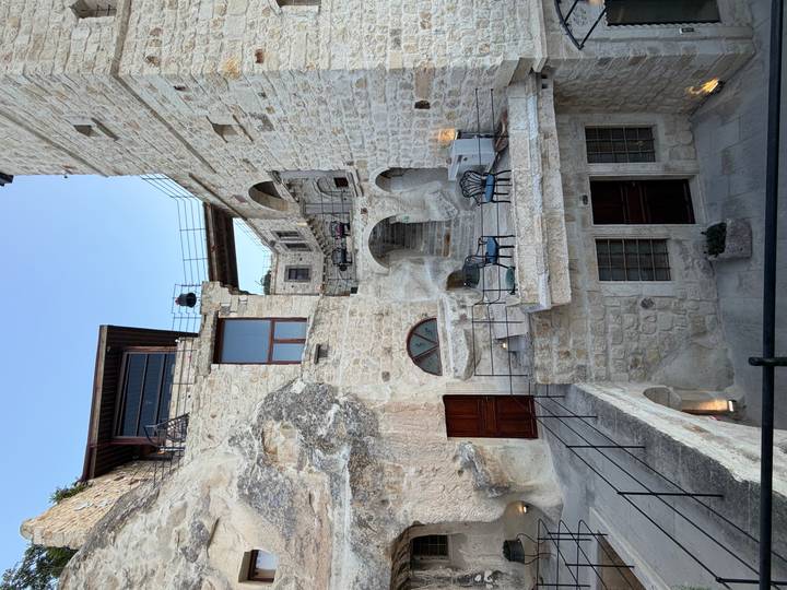Multi-level stone cave hotel with terraces and seating carved into the rock in Cappadocia.