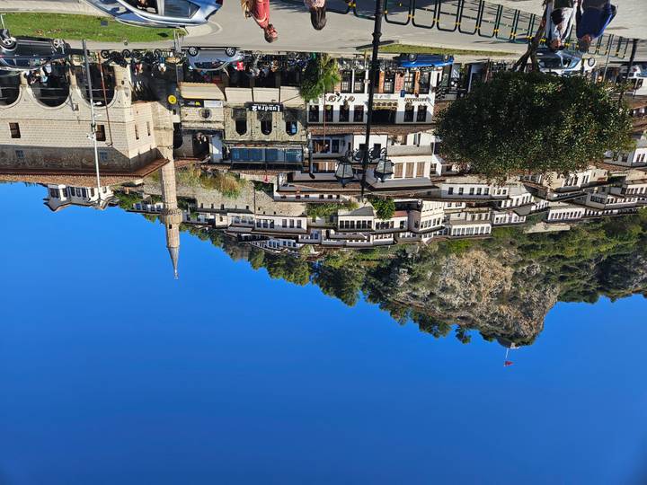 Ottoman houses cascade down hillside of Berat castle district beneath blue sky.