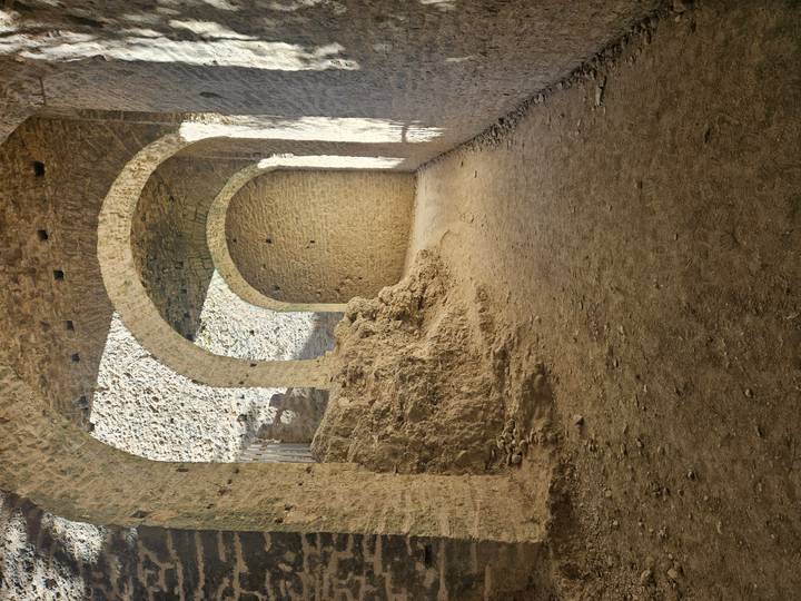 Arched stone corridor of ancient fortress lit by side light creating strong textures.
