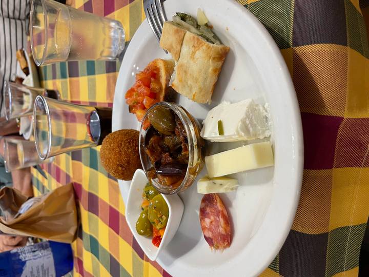 Italian antipasti plate with cheeses, olives, bruschetta, salami and a glass of red wine.