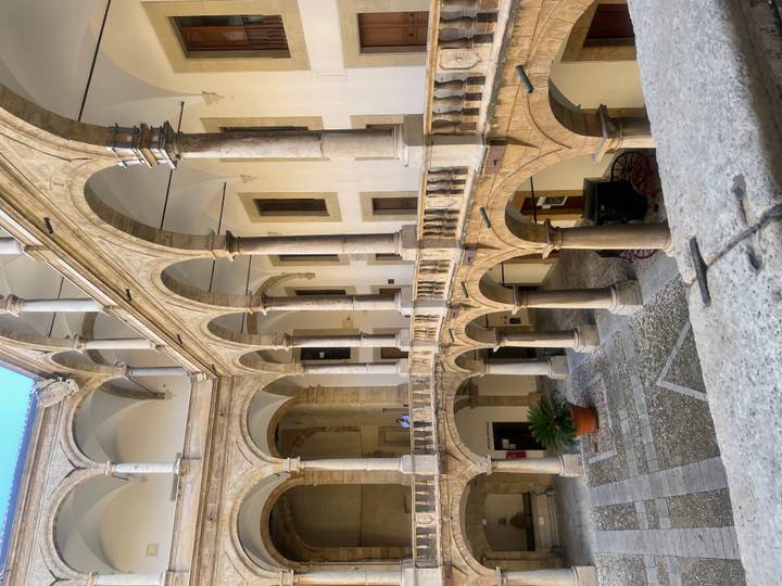 Elegant Renaissance cloister courtyard with arched colonnades and stone balustrades.