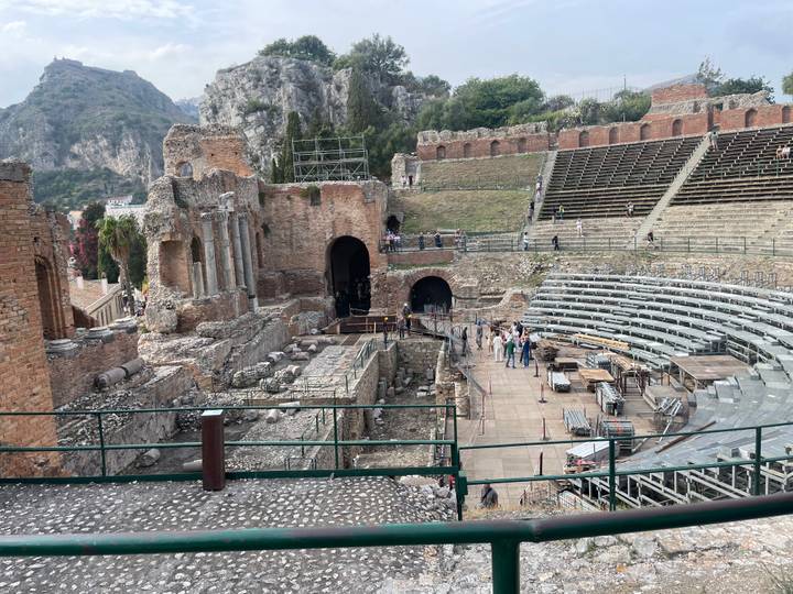View over the ancient Greco-Roman theatre ruins set on a hillside overlooking mountains.