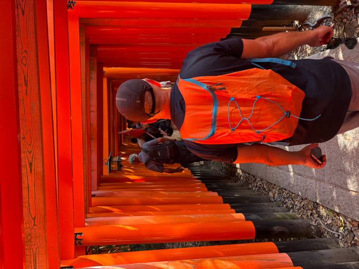 Visitors walking through the bright orange torii tunnel at Fushimi Inari Shrine.